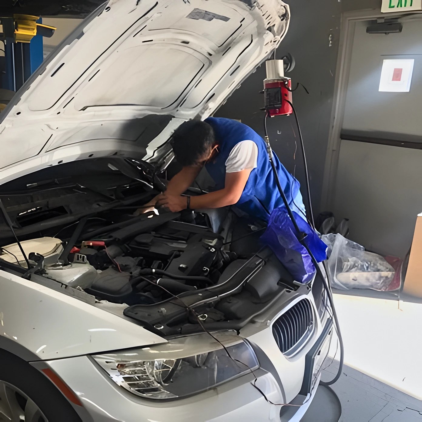 A technician working under the hood of a car at Fremont Auto Works